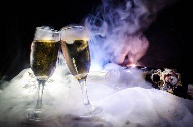 Yılbaşı kutlama ve arka plan flüt çifti şişe şampanya ile karlı koyu tonda sisli arka plan üzerinde Noel öznitelik (veya öğe). Seçici odak.