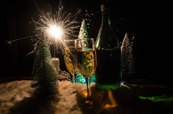 Flüt çifti ve şişe şampanya ile kar koyu arka plan üzerinde Noel ağacına yılbaşı kutlama arka plan.