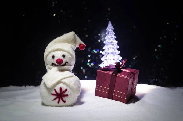 Új év. A hóember kirak ajándék részére a újév. Fehér hóember, karácsonyfa háttér este körül. Dekoráció játék — Stock Fotó