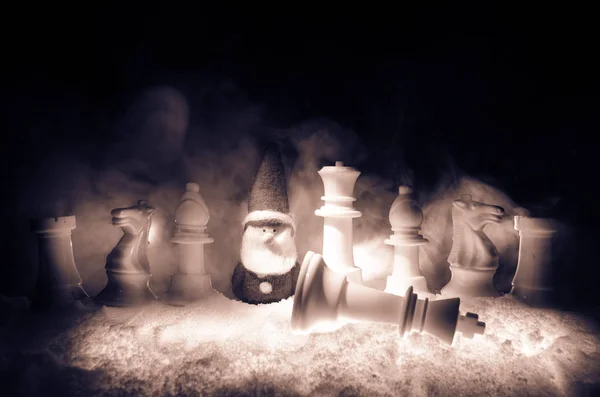 Schach im Schnee. Winterkonzept. Weihnachts- oder Neujahrsgeschenk auf einem Schachbrett mit Weihnachtsmann auf dunklem Hintergrund. Kopierraum. — Stockfoto