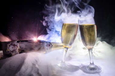 Yılbaşı kutlama ve arka plan flüt çifti şişe şampanya ile karlı koyu tonda sisli arka plan üzerinde Noel öznitelik (veya öğe). Seçici odak.