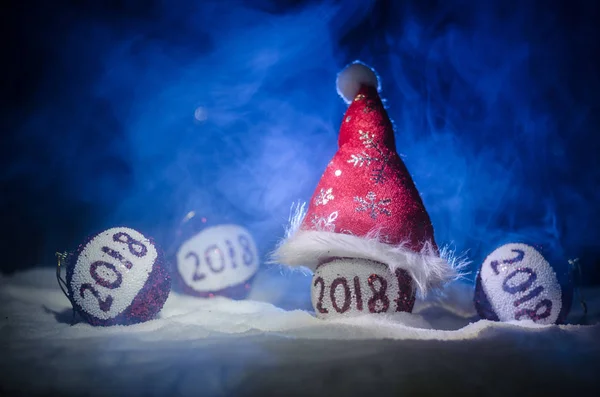 Rote Weihnachtskugeln mit Ziffer 2018 und Weihnachtsmann-Mütze auf Naturschnee-Hintergrund. Frohes neues Jahr 2018 konzept.copy space.selective focus. — Stockfoto