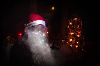 Noel Baba vaping elektronik sigara vape bulutlar karanlık bir tonda zemin üzerine geleneksel Noel Baba gibi giyinmiş. Seçici odak