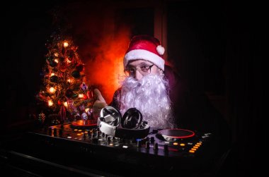 DJ Noel Baba biraz Noel neşesi kadar karıştırma. Karanlık disko kulüp arka plan tonda. Yeni yıl arifesi ışık ışınları durumda. Poster olarak kullanışlıdır. Seçici odak