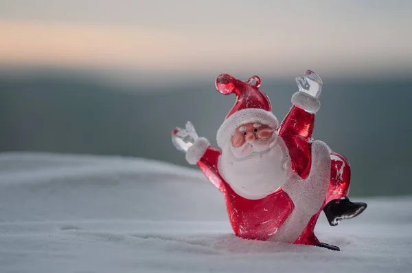 Feliz muñeco de Papá Noel en Navidad con árbol y nieve. Fondo exterior borroso. Santa Claus y Feliz Navidad modelo figura juguete detrás de la naturaleza desenfocada fondo — Foto de Stock