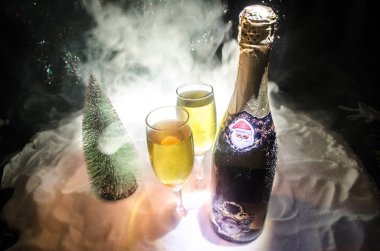 Yılbaşı kutlama ve arka plan flüt çifti şişe şampanya ile karlı koyu tonda sisli arka plan üzerinde Noel öznitelik (veya öğe). Seçici odak. Tebrik kartı olarak yararlı
