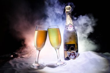 Yılbaşı kutlama ve arka plan flüt çifti şişe şampanya ile karlı koyu tonda sisli arka plan üzerinde Noel öznitelik (veya öğe). Seçici odak. Tebrik kartı olarak yararlı