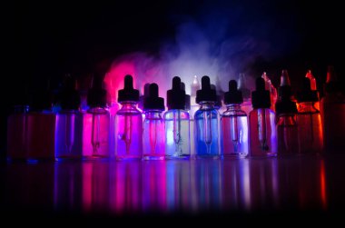 Vape kavramı. Duman bulutları ve vape sıvı şişe koyu arka plan üzerinde. Işık efektleri. Arka plan veya vape reklam veya vape arka plan olarak yararlı.