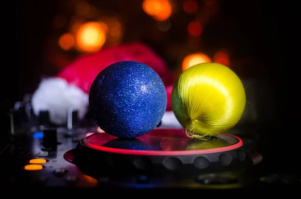 Dj mixer with headphones on dark nightclub background with Christmas tree New Year Eve. Close up view of New Year elements or symbols (Santa Clause, Snowman, Dog 2018, gift box) on a Dj table.