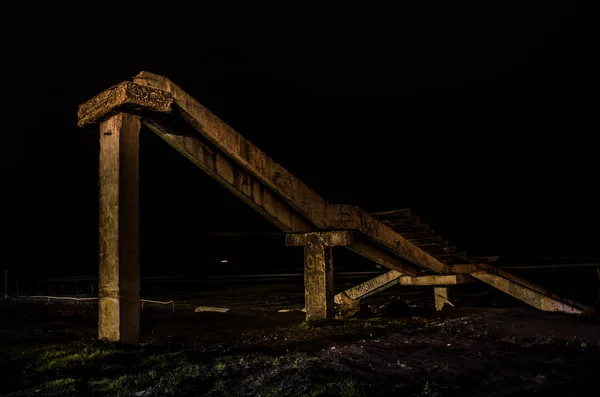 Fragment of the old conrete bridge near seaside of Nabran. North of Azerbaijan. Caspian Sea at night time with freezelight on it with different colors. View from under the bridge.