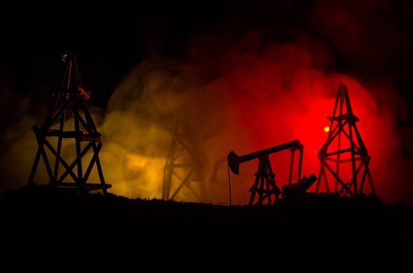 Oil pump oil rig energy industrial machine for petroleum, Group oil rigs and brightly lit industrial site at night. Toned.Background for design.