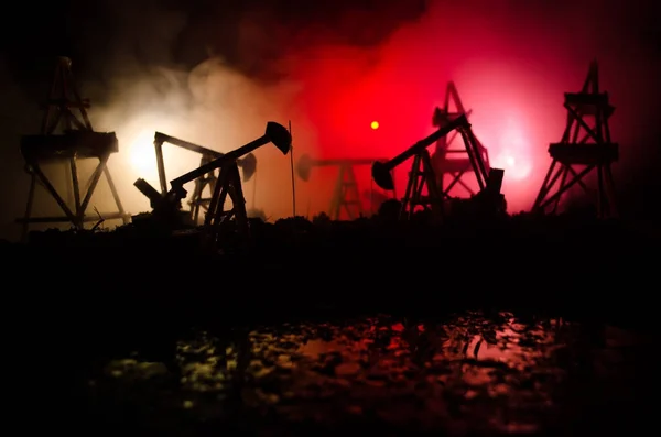 Oil pump oil rig energy industrial machine for petroleum, Group oil rigs and brightly lit industrial site at night. Toned.Background for design. Selective focus