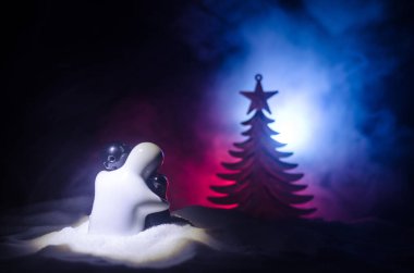 Aşk yeni yıl kavramı. Kız ve erkek seramik figürleri hugs her diğer, beyaz kar ve renkli kalp ve Noel ağacı bulanık koyu arka plan üzerinde duruyor. Boş alan.