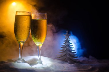 Yılbaşı kutlama ve arka plan flüt çifti şişe şampanya ile karlı koyu tonda sisli arka plan üzerinde Noel öznitelik (veya öğe). Seçici odak.