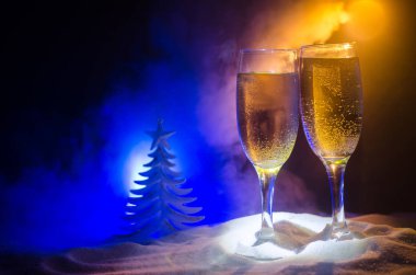 Yılbaşı kutlama ve arka plan flüt çifti şişe şampanya ile karlı koyu tonda sisli arka plan üzerinde Noel öznitelik (veya öğe). Seçici odak.