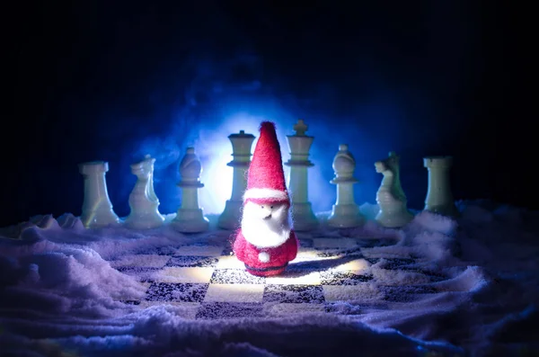 Chess in the snow. winter concept. Christmas or New Year present on a chessboard with Santa Claus on a dark background. Copy space.