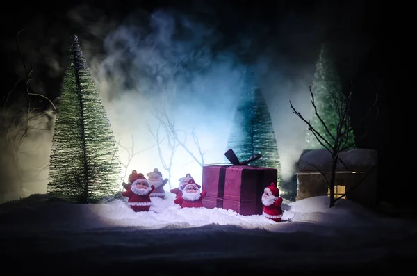 Glad jultomte docka på juletid med träd och snö. Färgglada bokeh bakgrund. Santa Clause och god jul modell figur leksak på mörk tonad — Stockfoto