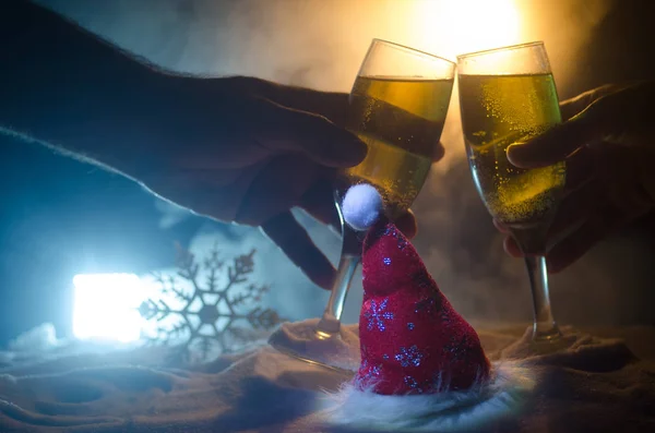 Capodanno sfondo celebrazione con coppia di flauti e bottiglia di champagne con attributi di Natale (o elementi) su sfondo nebbioso scuro nevoso tonica. Focus selettivo . — Foto Stock