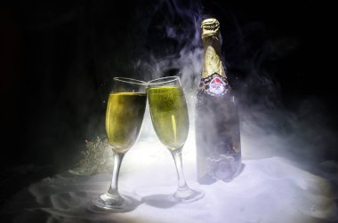 Yılbaşı kutlama ve arka plan flüt çifti şişe şampanya ile karlı koyu tonda sisli arka plan üzerinde Noel öznitelik (veya öğe). Seçici odak.