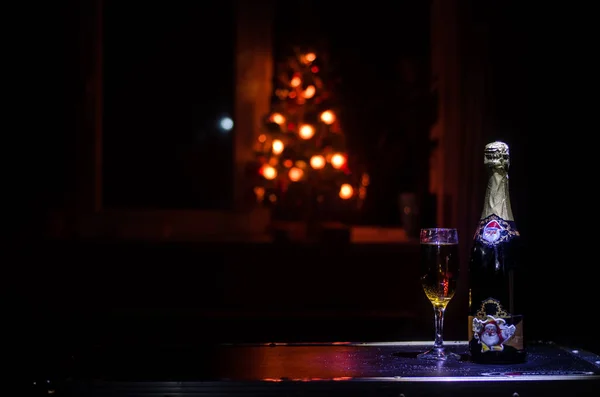 Fond de célébration du Nouvel An avec une paire de flûtes et une bouteille de champagne avec des attributs (ou des éléments) de Noël sur fond brouillard nuageux foncé enneigé. Concentration sélective — Photo