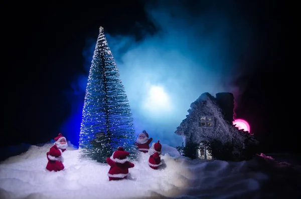 Szczęśliwy lalka Santa Claus na Boże Narodzenie w drzewa i śnieg. Bokeh kolorowe tło. Śnięty Mikołaj i Wesołych Świąt zabawka rysunek modelu na ciemnym stonowanych — Zdjęcie stockowe