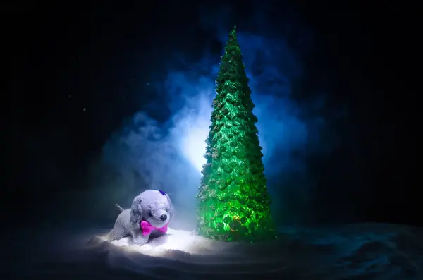 Chien jouet - symbole du Nouvel An sous la neige sur fond de branches de sapin. Chien de jouet comme symbole du Nouvel An 2018 avec un Noël attribue l'inscription du Nouvel An — Photo