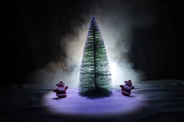 Glückliche Weihnachtsmann-Puppe zu Weihnachten mit Baum und Schnee. bunte Bokeh Hintergrund. Weihnachtsmann-Klausel und frohe Weihnachten Modell Figurenspielzeug auf dunkel getönten — Stockfoto