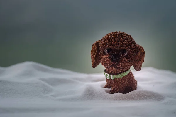 Toy dog - a symbol of the new year under the snow against the background of fir branches. Toy\'s dog as a symbol of 2018 New Year with a Christmas attributes