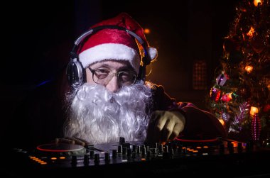 DJ Noel Baba biraz Noel neşesi kadar karıştırma. Karanlık disko kulüp arka plan tonda. Yeni yıl arifesi ışık ışınları durumda. Poster olarak kullanışlıdır. Seçici odak