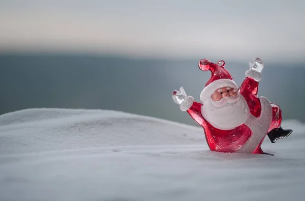 Feliz muñeco de Papá Noel en Navidad con árbol y nieve. Fondo exterior borroso. Santa Claus y Feliz Navidad modelo figura juguete detrás de la naturaleza desenfocada fondo — Foto de Stock