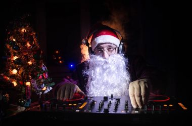 DJ Noel Baba biraz Noel neşesi kadar karıştırma. Karanlık disko kulüp arka plan tonda. Yeni yıl arifesi ışık ışınları durumda. Poster olarak kullanışlıdır. Seçici odak
