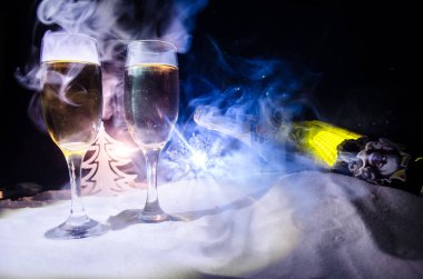 Yılbaşı kutlama ve arka plan flüt çifti şişe şampanya ile karlı koyu tonda sisli arka plan üzerinde Noel öznitelik (veya öğe). Seçici odak. Tebrik kartı olarak yararlı