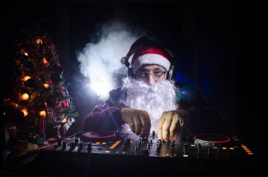 DJ Noel Baba biraz Noel neşesi kadar karıştırma. Karanlık disko kulüp arka plan tonda. Yeni yıl arifesi ışık ışınları durumda. Poster veya tebrik kartı olarak kullanışlıdır. Seçici odak