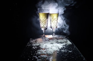 Yılbaşı kutlama ve arka plan flüt çifti şişe şampanya ile karlı koyu tonda sisli arka plan üzerinde Noel öznitelik (veya öğe). Seçici odak.