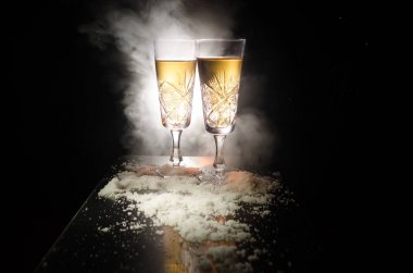 Yılbaşı kutlama ve arka plan flüt çifti şişe şampanya ile karlı koyu tonda sisli arka plan üzerinde Noel öznitelik (veya öğe). Seçici odak. Tebrik kartı olarak yararlı