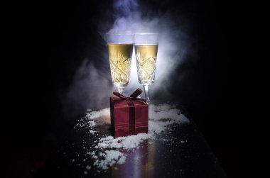 Yılbaşı kutlama ve arka plan flüt çifti şişe şampanya ile karlı koyu tonda sisli arka plan üzerinde Noel öznitelik (veya öğe). Seçici odak. Tebrik kartı olarak yararlı