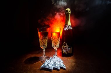 Yılbaşı kutlama ve arka plan flüt çifti şişe şampanya ile karlı koyu tonda sisli arka plan üzerinde Noel öznitelik (veya öğe). Seçici odak. Tebrik kartı olarak yararlı