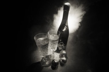 Yılbaşı kutlama ve arka plan flüt çifti şişe şampanya ile karlı koyu tonda sisli arka plan üzerinde Noel öznitelik (veya öğe). Seçici odak. Tebrik kartı olarak yararlı