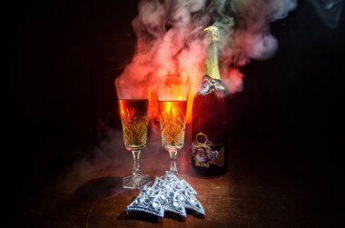 Yılbaşı kutlama ve arka plan flüt çifti şişe şampanya ile karlı koyu tonda sisli arka plan üzerinde Noel öznitelik (veya öğe). Seçici odak. Tebrik kartı olarak yararlı