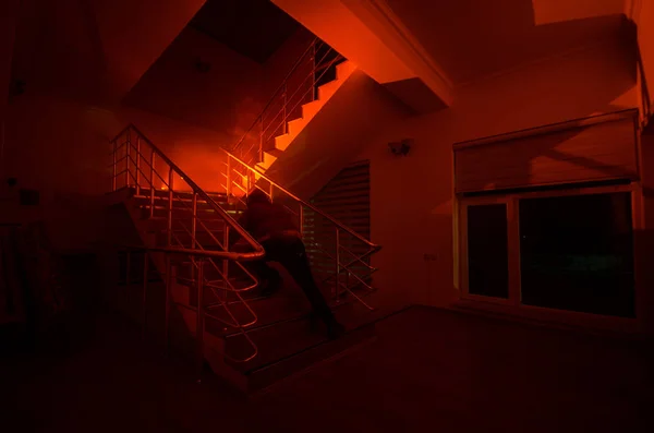 Ghost in Haunted House at stairs, Mysterious silhouette of ghost man with light at stairs, Horror scene of scary ghost spooky llights . Scary hall. Halloween background. Selective focus