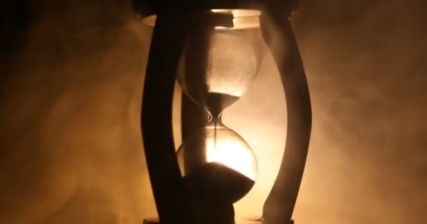 時間の概念 暗いトーンの背景 または煙 最後の下の時間のシンボルに煙で回転砂時計時計のシルエット — ストック動画