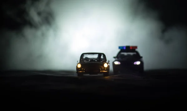 Jouet BMW voiture de police pourchassant une voiture Ford Thunderbird la nuit avec fond de brouillard. Décoration de jouets scène sur la table. Focus sélectif - 11 JAN 2018, BAKU AZERBAIJAN — Photo