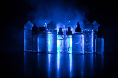 Vape kavramı. Duman bulutları ve vape sıvı şişe koyu arka plan üzerinde. Işık efektleri