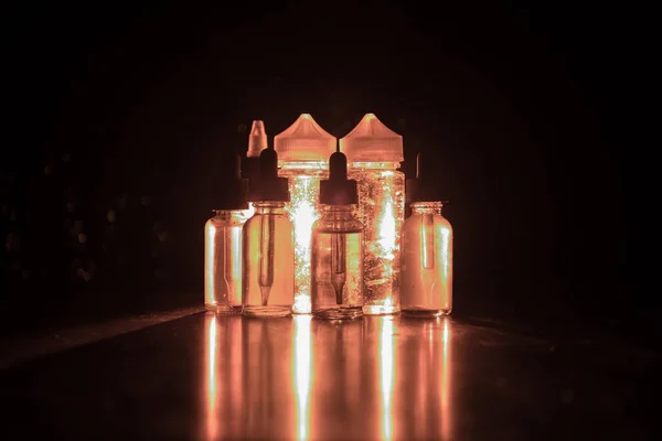 Vape Konzept. Rauchwolken und Dampfflaschen auf dunklem Hintergrund. Lichteffekte — Stockfoto