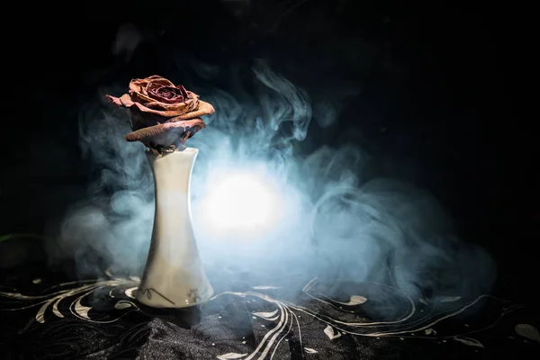 Uma rosa murcha significa amor perdido, divórcio ou um relacionamento ruim, rosa morta no fundo escuro com fumaça — Fotografia de Stock