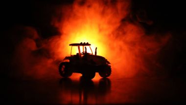 Traktör karanlık sisli arka plan ile gece silüeti. Tonda. Yanan araç.