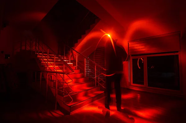 Fantasma en casa embrujada en las escaleras, silueta misteriosa del hombre fantasma con luz en las escaleras, escena de horror de fantasmas aterradores luces espeluznantes. Sala de miedo. Fondo de Halloween. Enfoque selectivo — Foto de Stock