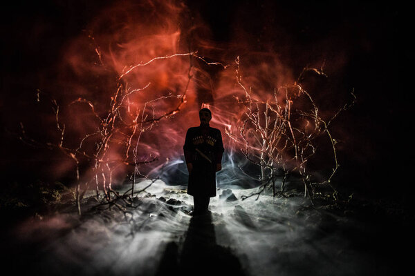 strange silhouette in a dark spooky forest at night, mystical landscape surreal lights with creepy man. Toned