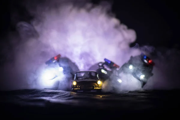 Juguete BMW Police y Toyota FJ Cruiser coches persiguiendo un Ford Thunderbird coche por la noche con fondo de niebla. Escena de decoración de juguetes en la mesa .- 11 ENE 2018, BAKU AZERBAIJAN —  Fotos de Stock