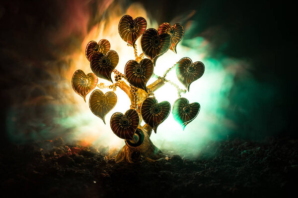 Abstract field with tree and hearts on it behind dark foggy toned sky. Love tree of dreams. Valentine concept background